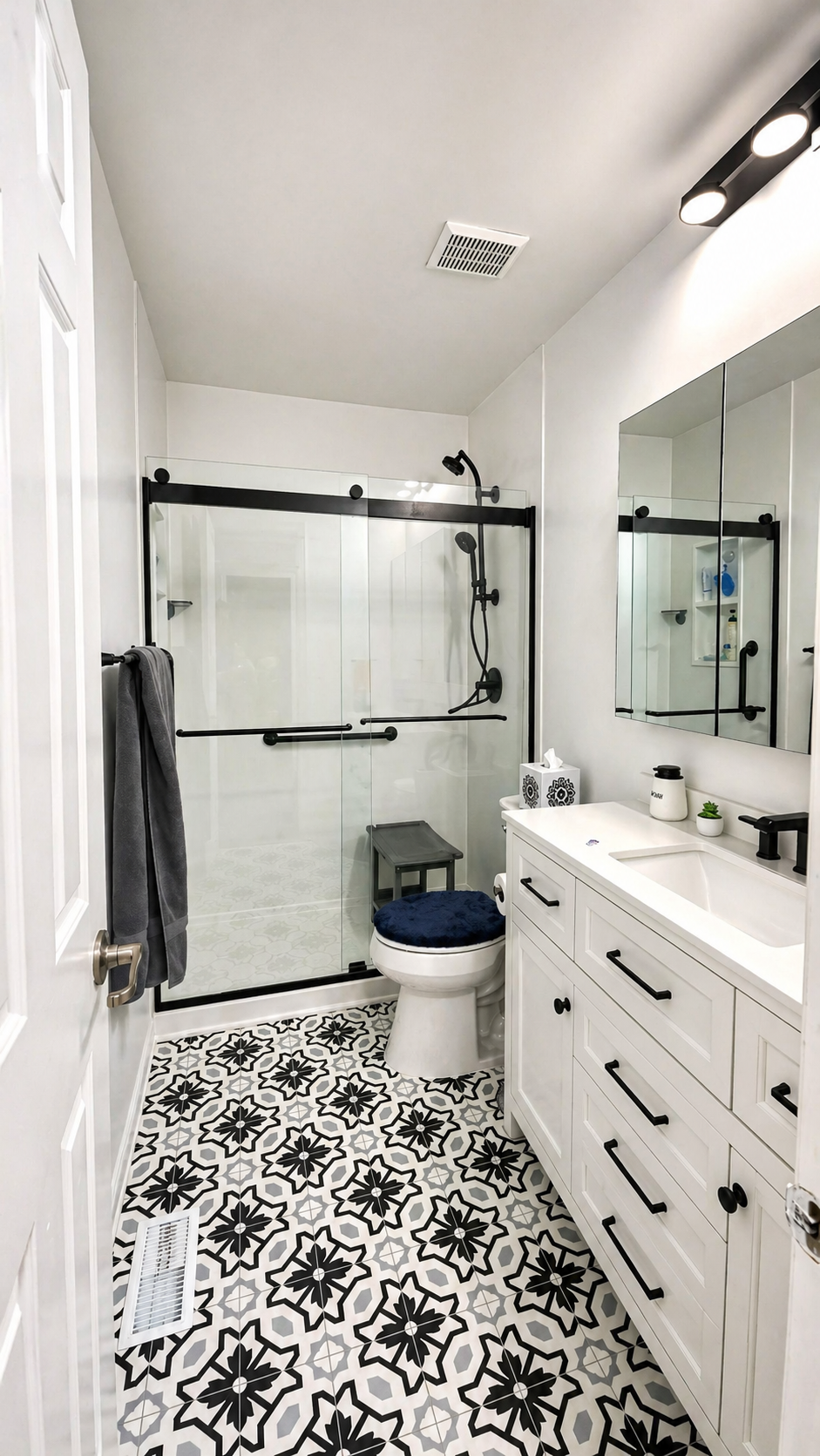 After — Greaves Construction walk-in glass shower with patterned tile floor, black fixtures, and new vanity.