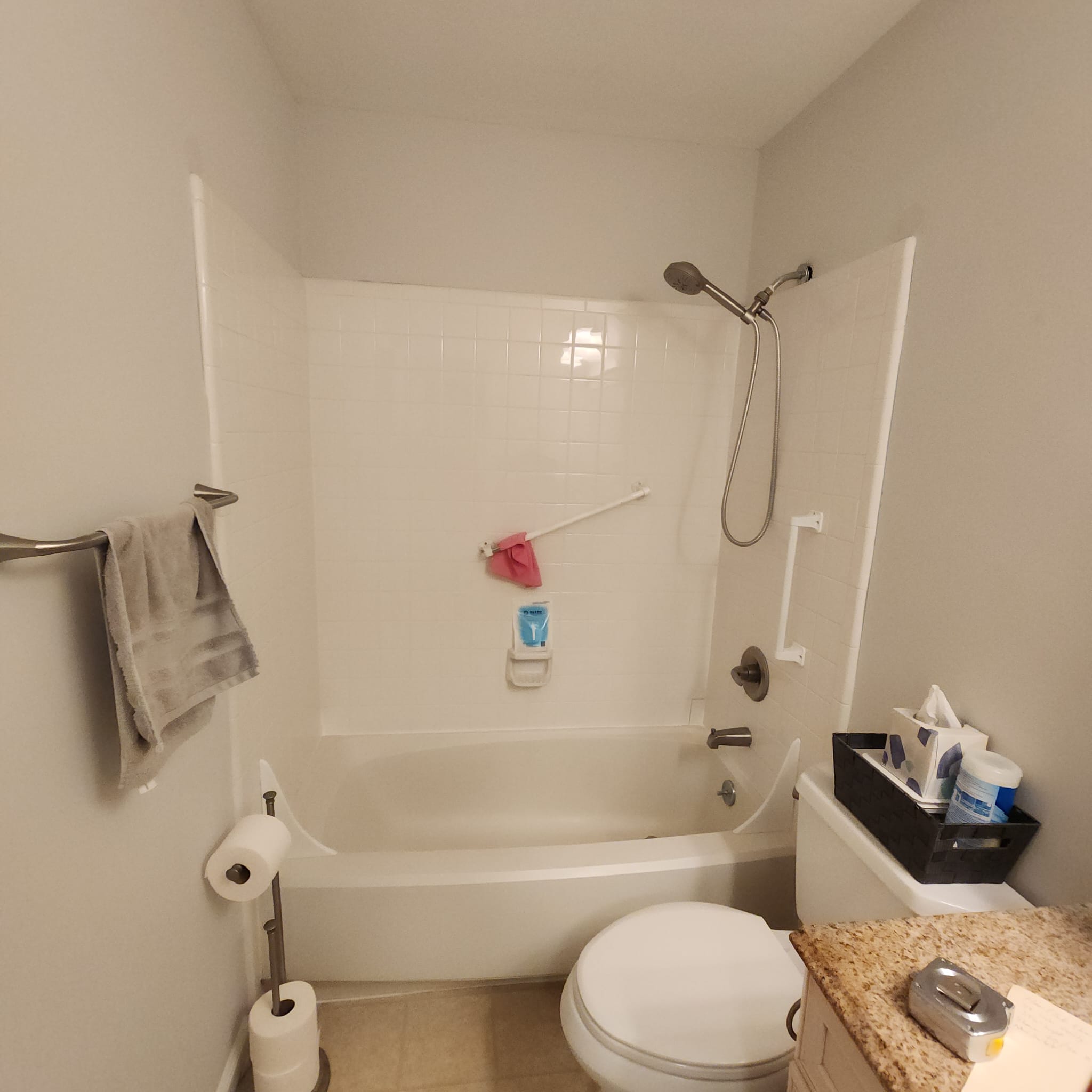 Before — original builder-grade tub/shower with white tile surround.